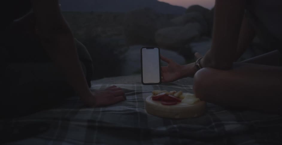 Two women are watching a phone at a picnic