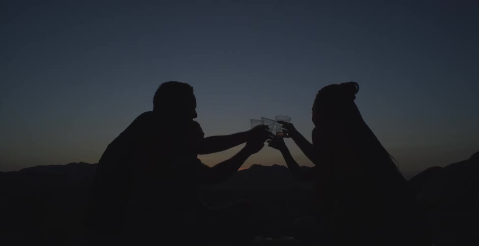 People are toasting drinks at sunset