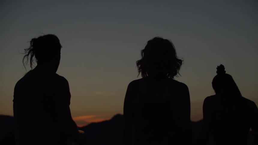 Silhouette of a man and two women in an outdoor setting at dark dawn
