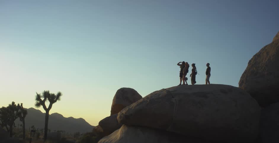 Four travelers on a trail on top of a rock at dawn