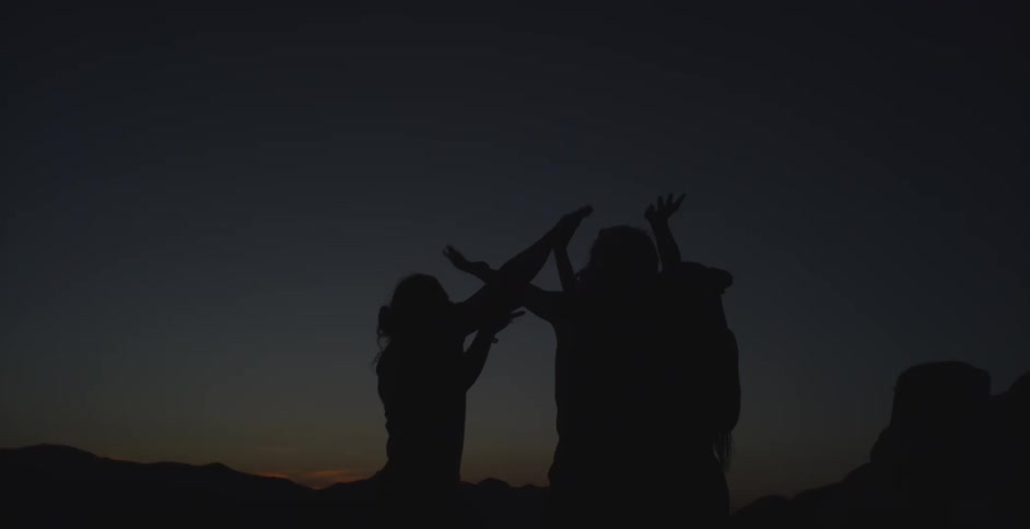 Silhouette of three people outdoors celebrating happily in a dark dawn