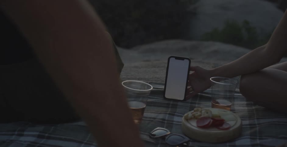 Person holding a smartphone and showing it to another person next to them in an outdoor setting