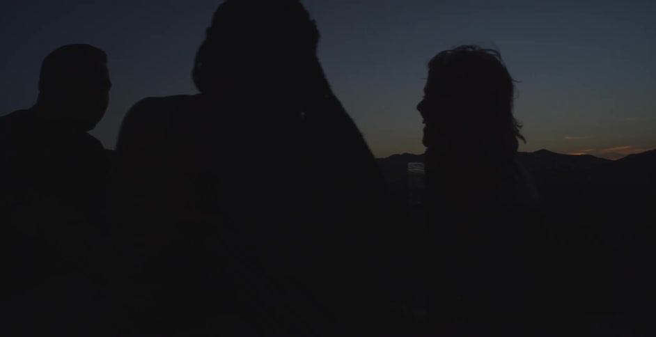 Friends sit in the dark of the sunset talking