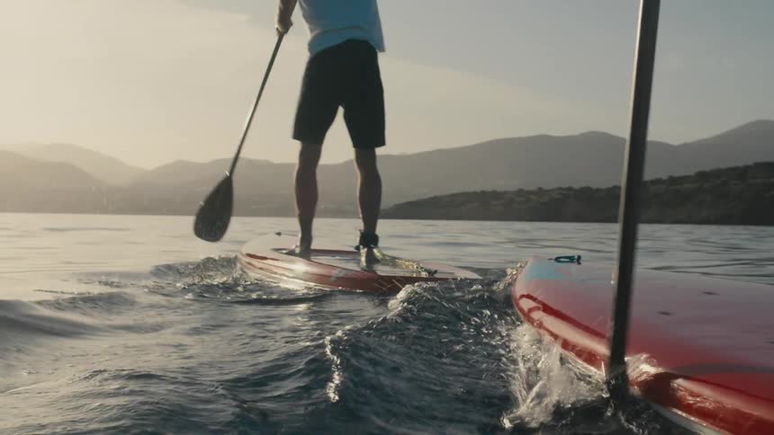 Two people stand up paddling in the ocean