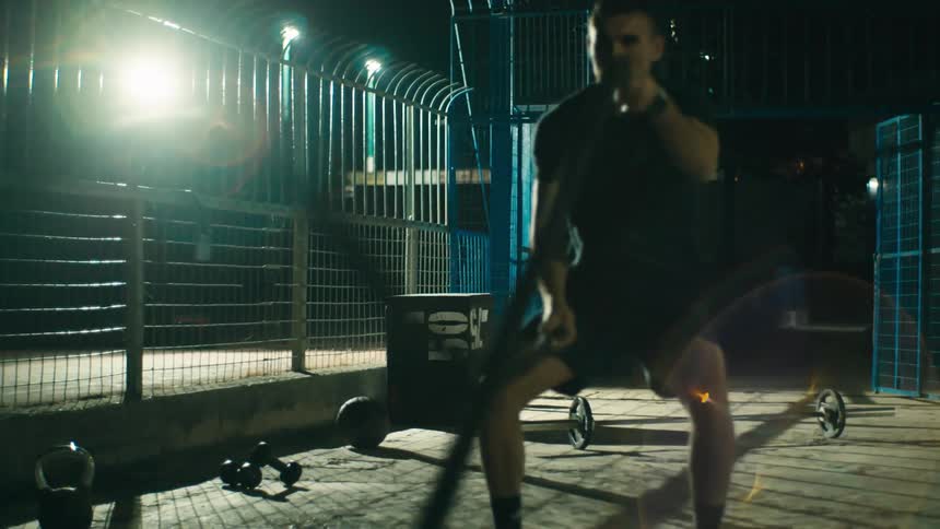 Man hitting ropes in an outdoor gym at night