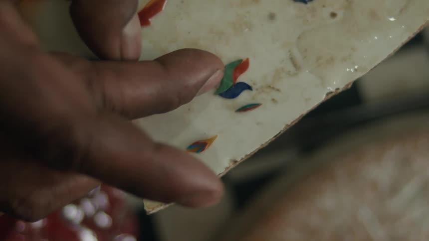 An artist is putting small pieces of color on the glue