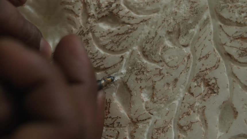 Closeup of a person with a tool carving marble