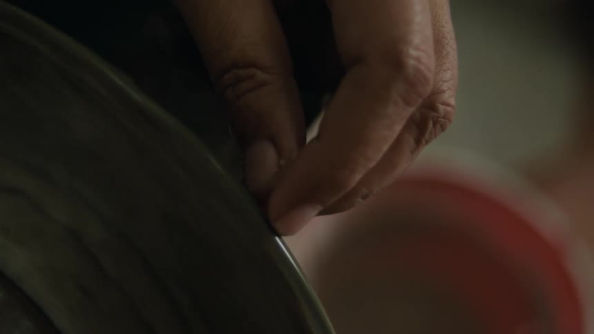 Hand holding a small tool and tuning it on a machine
