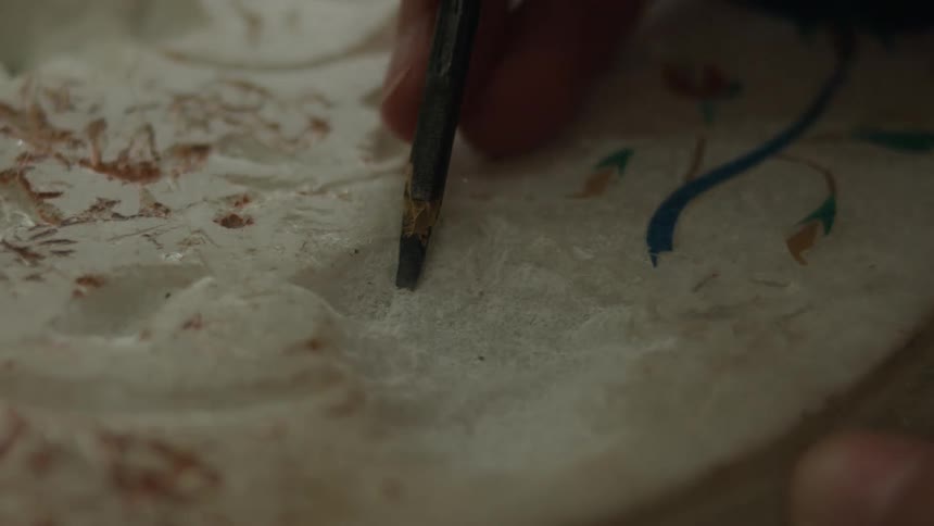 Hand with a tool performing sculpture on a marble