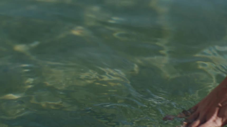 Womans hand in crystal clear ocean waters