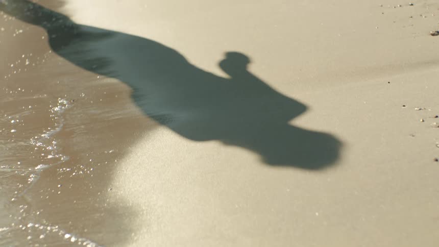 A woman is walking on the beach on a sunny day