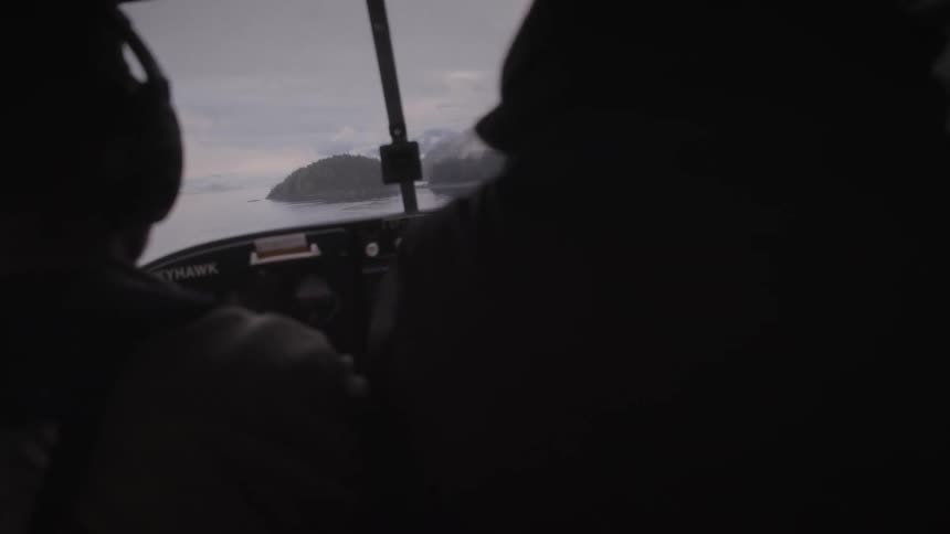 Two people in a helicopter cabin on a flight over the sea
