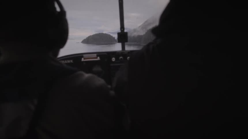 Two people inside the cockpit of a helicopter in midflight