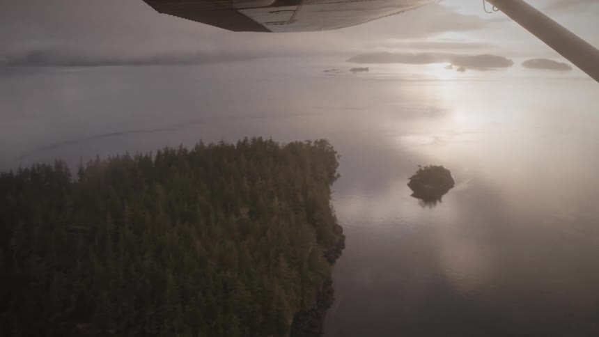 An airplane is flying over a lake at sunset