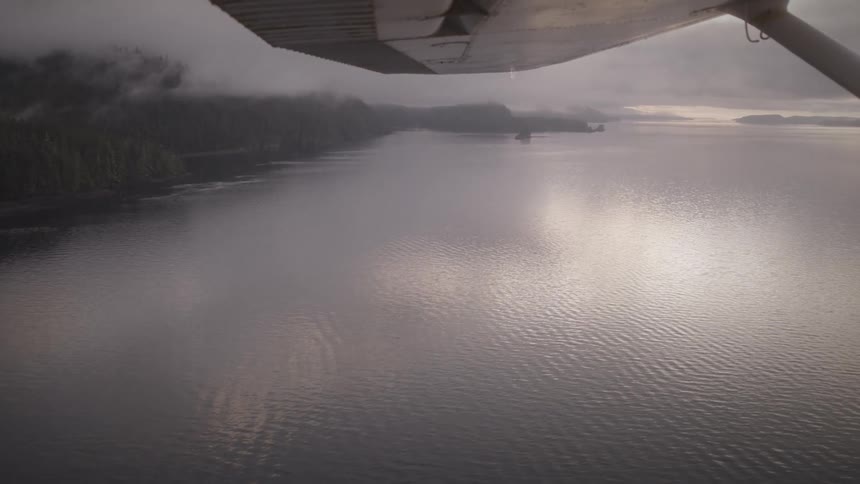 A view from under the wing of a small plane flying over a lake
