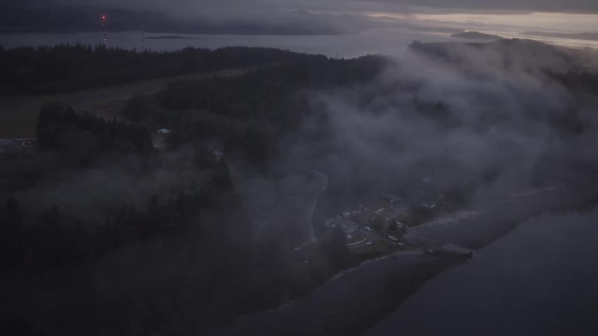 Heavy fog covers the homes on the shore