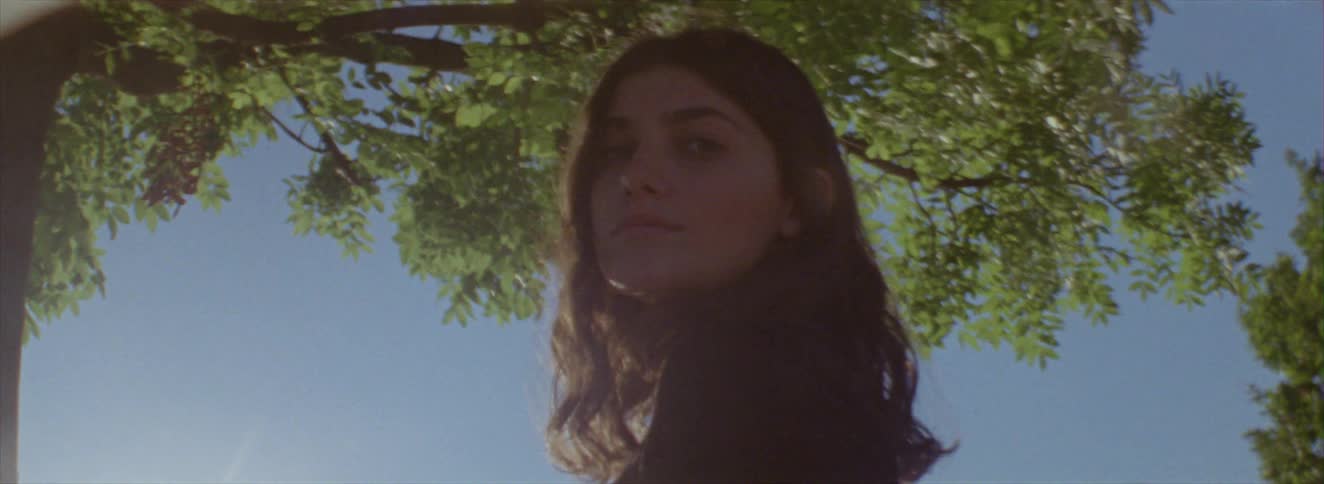 A woman is standing under a tree