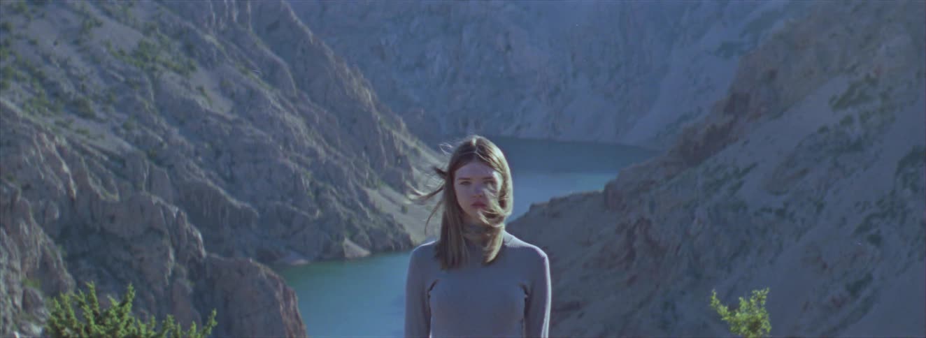 Young blonde woman in a mountainous landscape walking and a river in the background