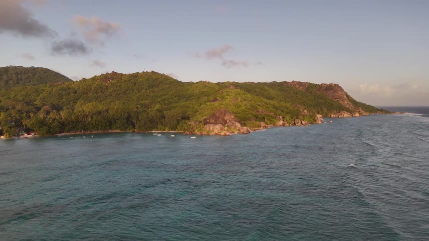Sea with gentle waves arrives at a wooded island