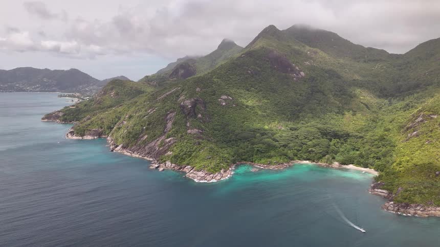 Mountains covered in dense vegetation border a coastline of turquoise waters with small isolated beaches