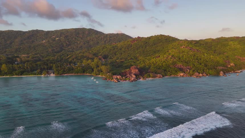 A mountainous island covered with vegetation is surrounded by the ocean