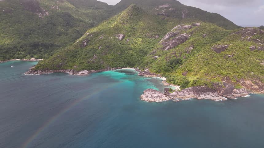 Aerial view of towering mountains by the sea on a cloudy day