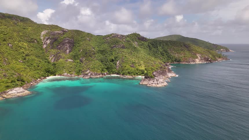 Towering forested mountains surrounded by the sea on a cloudy day