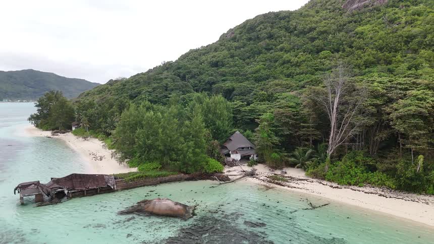 Secluded wooden hut nestled in lush trees on white sandy beach and crystal clear water
