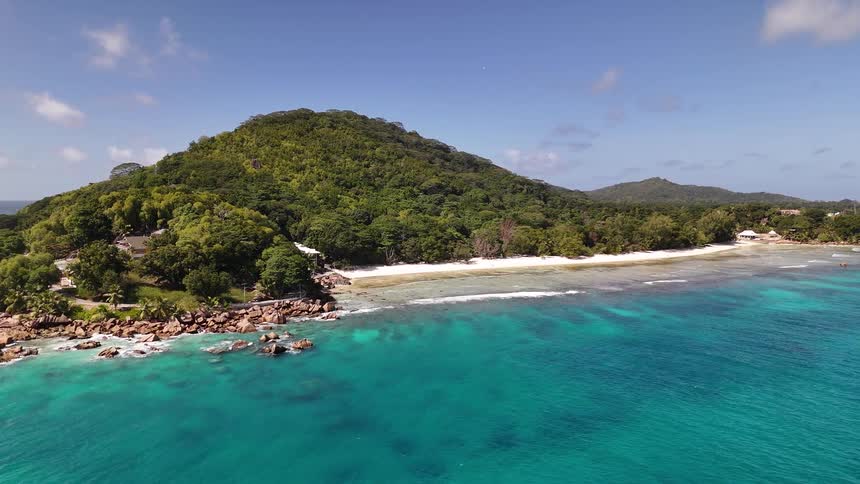 Aerial panorama of forested mountains by the sea with a turquoise beach