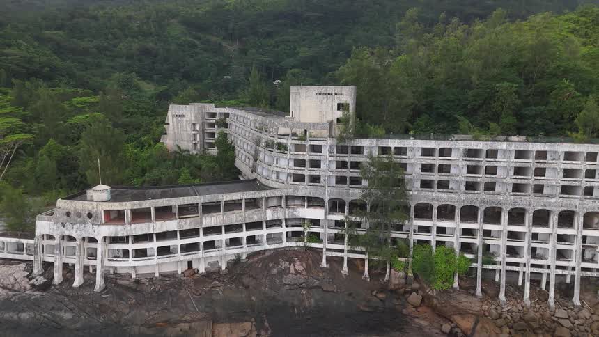 The abandoned mah beach hotel in seychelles is surrounded by green vegetation at midday
