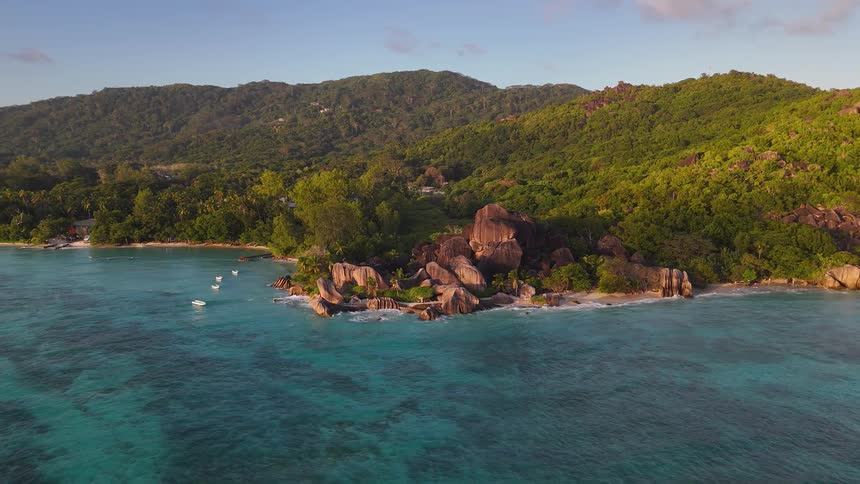 Rocky tropical shore meets turquoise waters and green hills