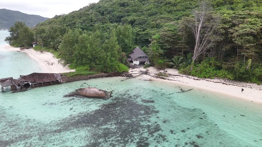 Secluded wooden hut nestled in trees on white sandy beach and crystal clear water