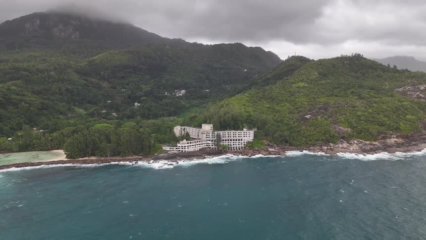 Aerial of isolated waterfront resort nestled in the hillside along rocky shoreline on an island