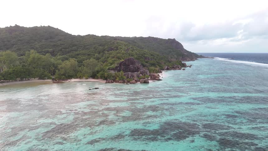 Aerial panorama of a turquoise blue sea with a wooded coastline