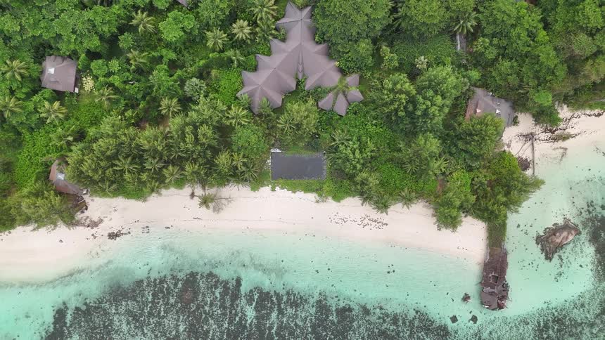 Aerial view of a beachfront resort nestled in a tropical rainforest