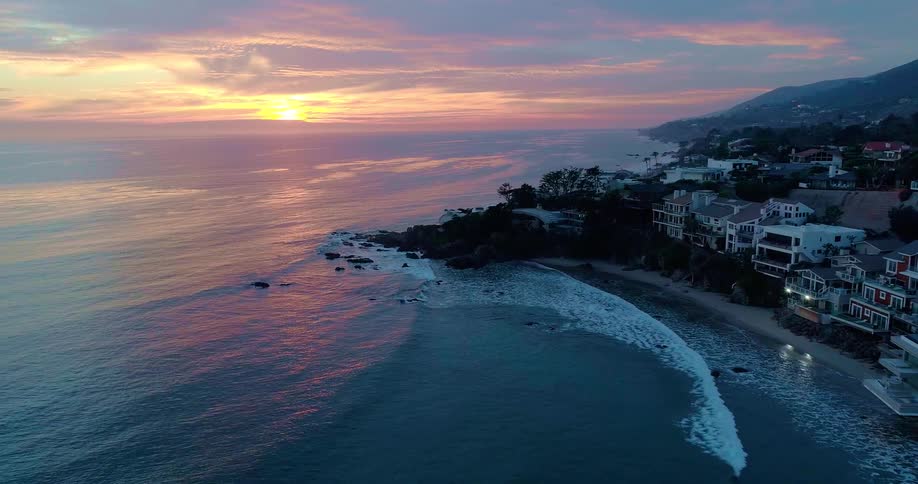 Aerial view of Malibu at sunset with waves gently washing the shore