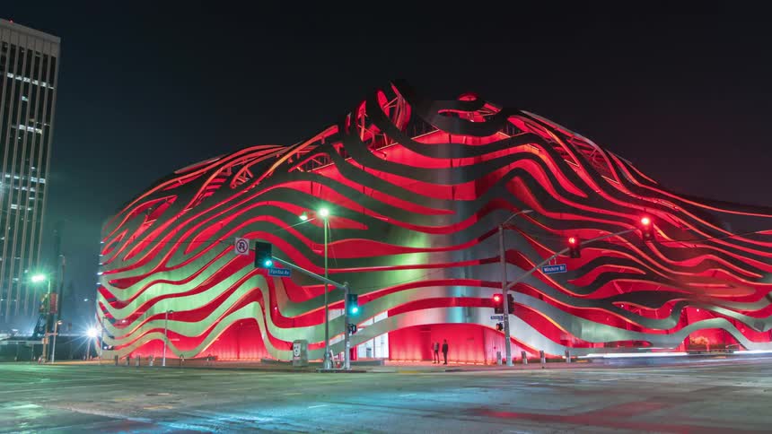 The busy intersection of Wilshire and Fairfax with the glowing red Petersen Automotive Museum in Los Angeles