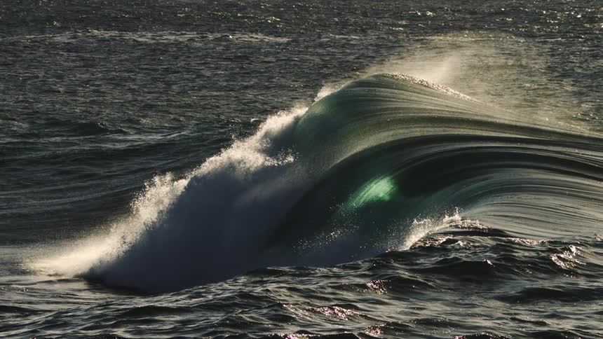 A massive wave crashes bursting into white spray and foam