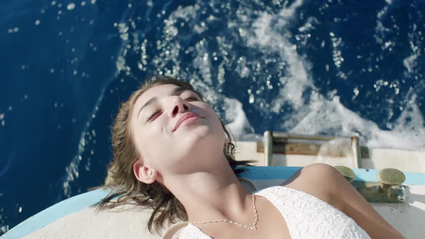 Woman relaxes on boat deck with ocean backdrop