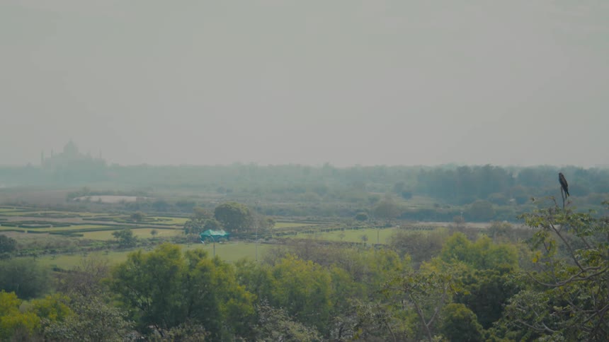 Wide rural fields stretch across the landscape under a hazy sky