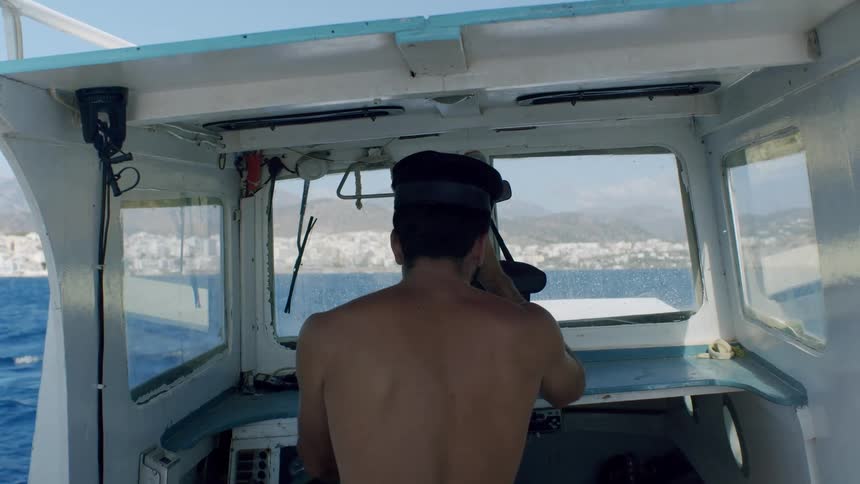 Man steering a small boat toward the horizon under a bright sky