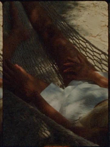 Woman lying down relaxing in a hammock on the beach sand