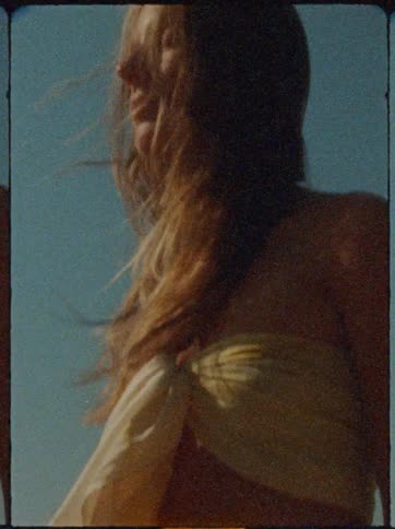 Woman wears fabric across her breasts on a windy summer day
