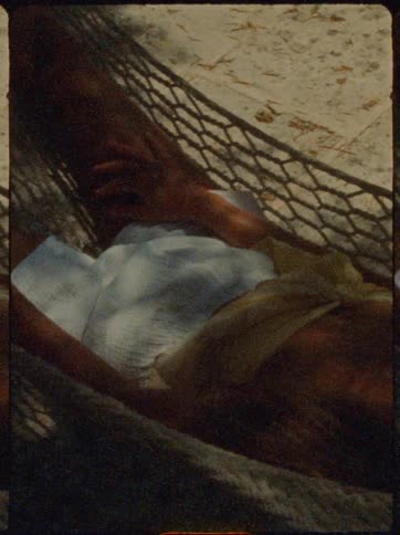 Woman lying in a hammock in a sandy beach environment