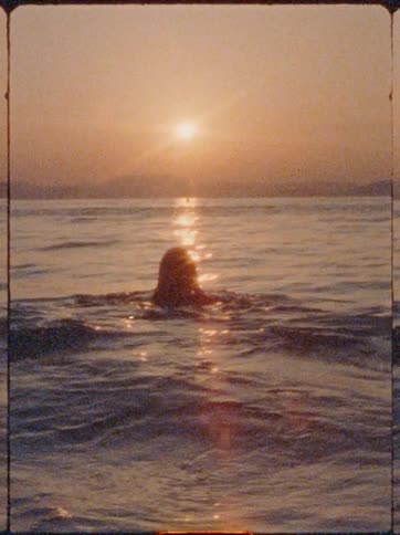 Silhouette of a woman swimming in the sea in the late afternoon with the sun on the horizon