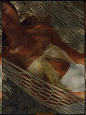 Woman relaxes in a sunlit hammock eyes closed and dappled in soft shadows