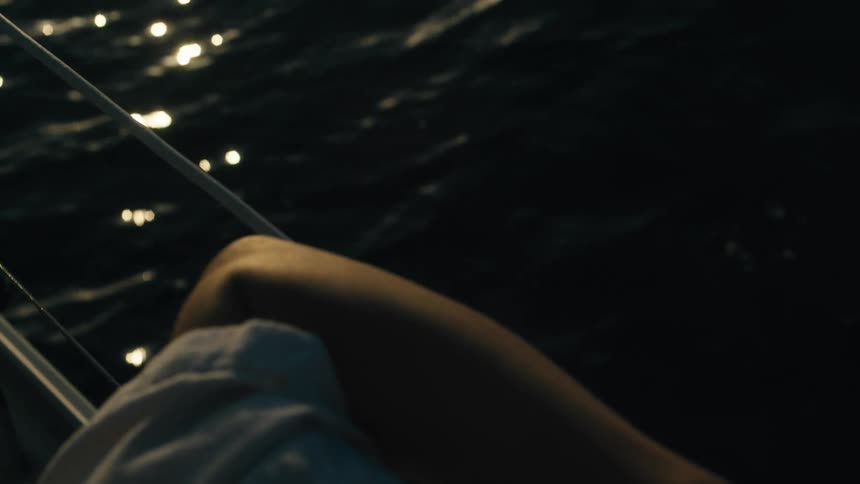 Persons arm resting on a metal support of a boat moving at sea