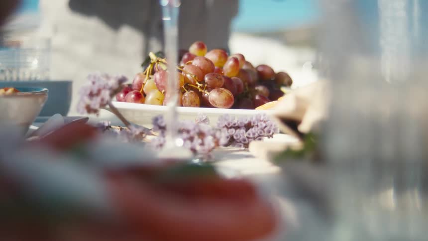 Pair of gloved hands placing a plate of fresh purple grapes on a table