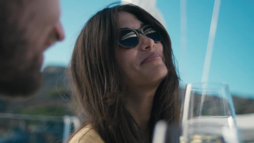 Woman with happy expression on a yacht with sunglasses next to a man
