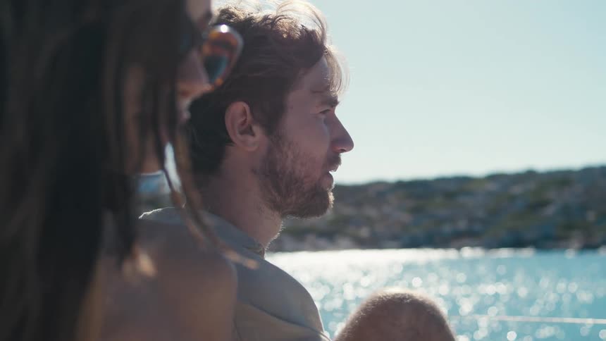 Man drinking coffee lakeside as his partner sits nearby
